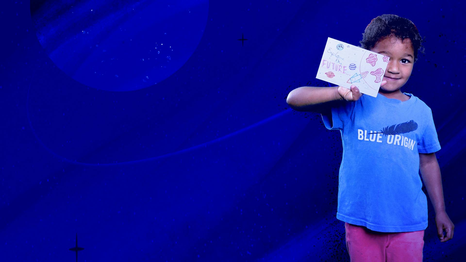 A young girl in a Blue Origin T-shirt holds up a paper postcard covered in drawings